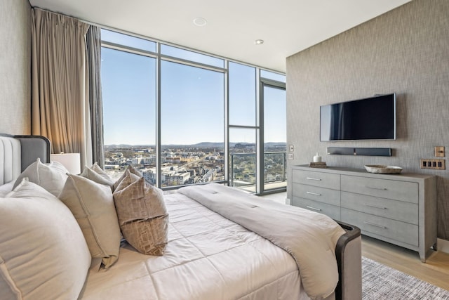 bedroom with a wall of windows and light wood-style floors