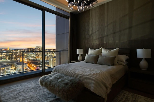 bedroom featuring floor to ceiling windows, a chandelier, and a city view