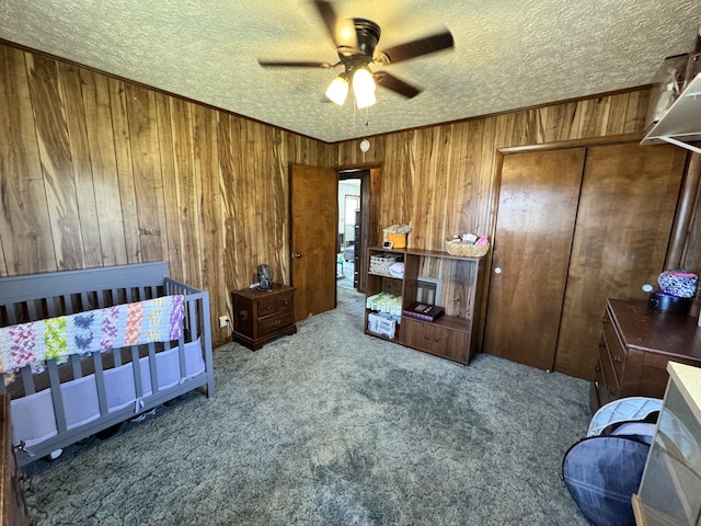 bedroom featuring carpet floors, a closet, wood walls, and a textured ceiling