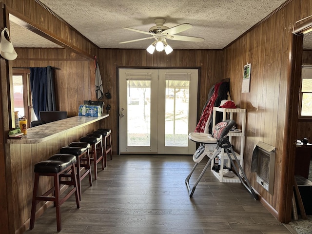 interior space featuring dark wood-type flooring, wooden walls, a textured ceiling, and heating unit