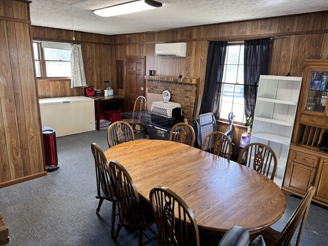 dining area with carpet floors, wood walls, a textured ceiling, and a wall mounted AC