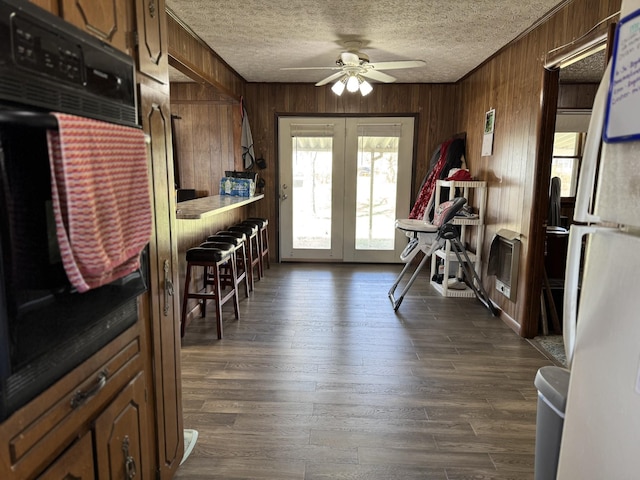 interior space with a textured ceiling, dark wood-type flooring, and wood walls