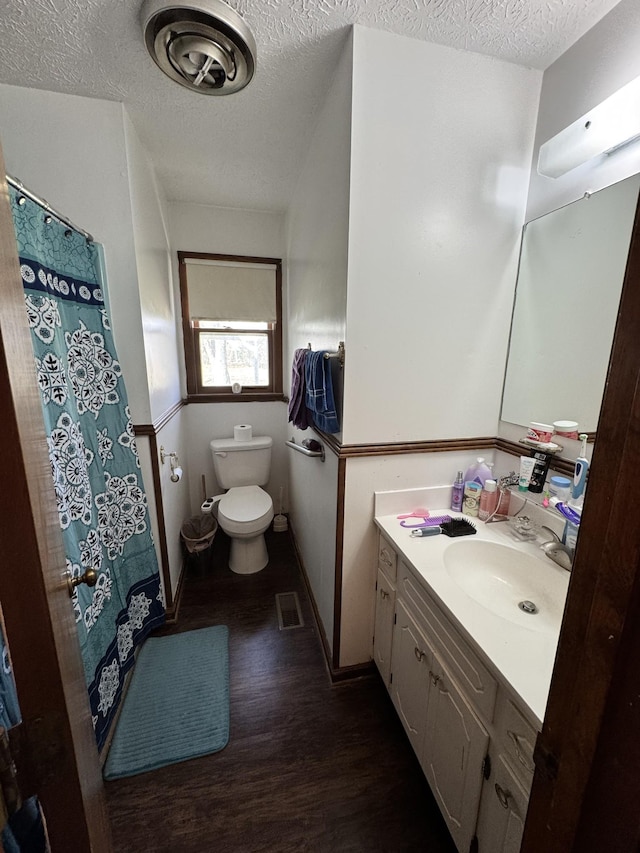 full bathroom with a textured ceiling, toilet, wood finished floors, visible vents, and vanity