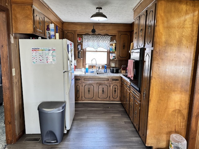 kitchen featuring a textured ceiling, dark wood-style flooring, a sink, light countertops, and freestanding refrigerator