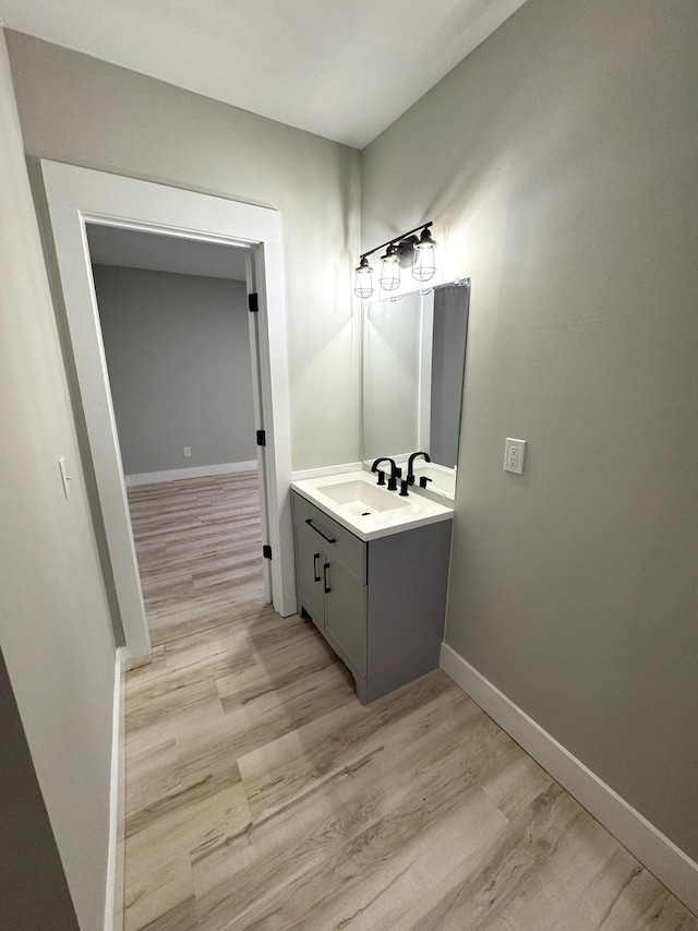 bathroom featuring vanity, baseboards, and wood finished floors