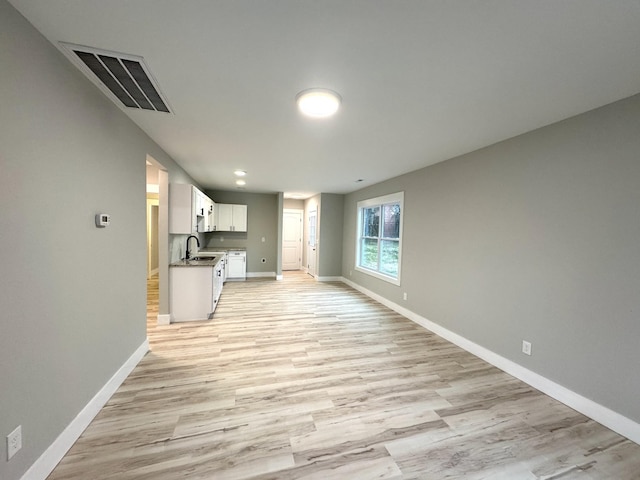 interior space with light wood-style floors, visible vents, a sink, and baseboards