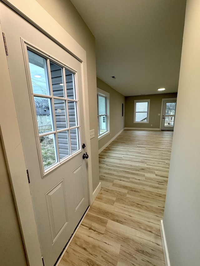 doorway to outside with light wood finished floors and baseboards
