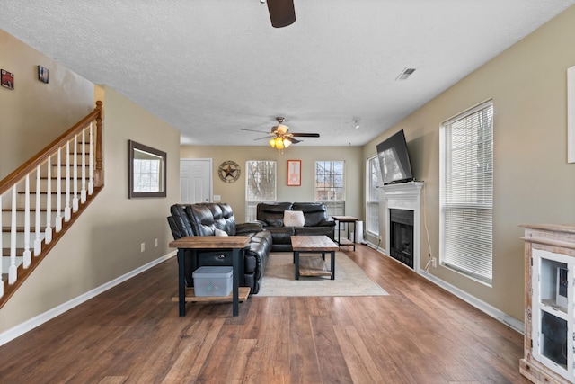 living area featuring baseboards, visible vents, stairway, wood finished floors, and a fireplace