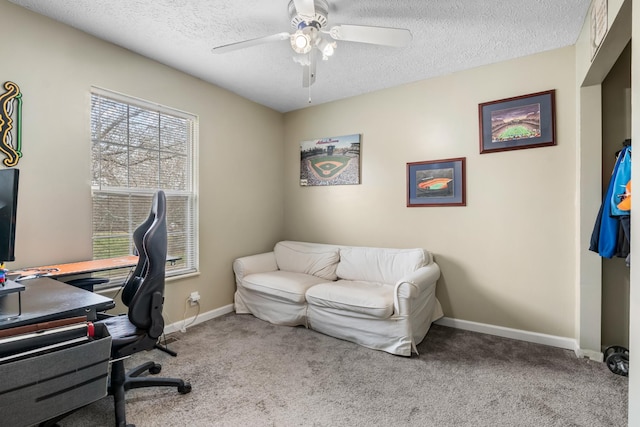 carpeted office space featuring ceiling fan, baseboards, and a textured ceiling