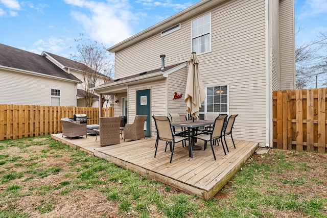 rear view of house with outdoor dining space, a fenced backyard, and a wooden deck