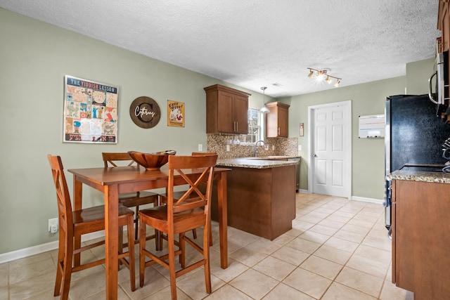 dining area featuring light tile patterned floors, baseboards, and a textured ceiling