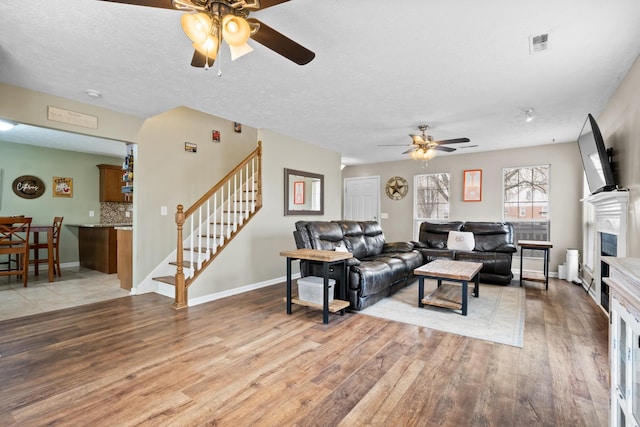 living area with light wood finished floors, stairway, and a fireplace