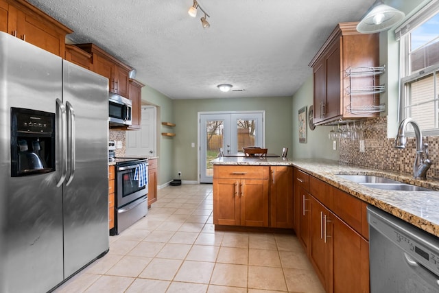 kitchen featuring light tile patterned flooring, stainless steel appliances, a peninsula, a sink, and french doors