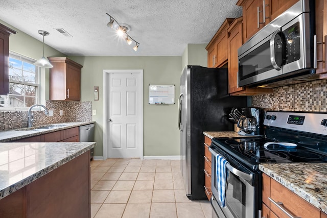 kitchen featuring light tile patterned floors, visible vents, appliances with stainless steel finishes, brown cabinets, and a sink