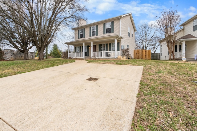 colonial inspired home with a porch, a chimney, a front lawn, and fence