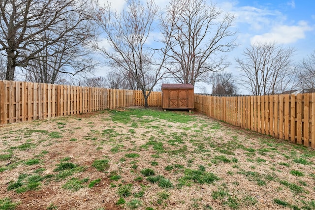 view of yard with a fenced backyard, a storage unit, and an outbuilding