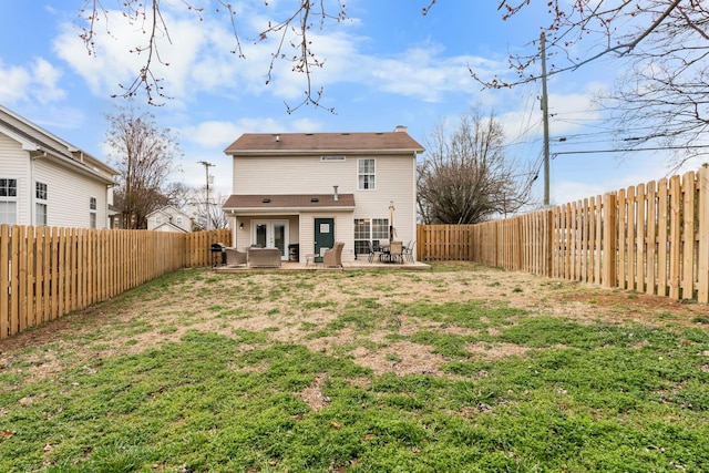 back of property featuring a yard, french doors, and a fenced backyard