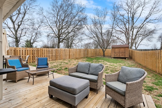 wooden terrace with an outdoor hangout area, a storage unit, an outbuilding, and a fenced backyard