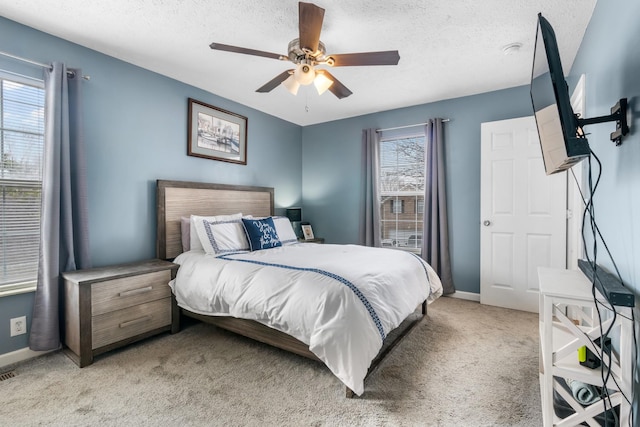 bedroom featuring light colored carpet, a textured ceiling, and baseboards