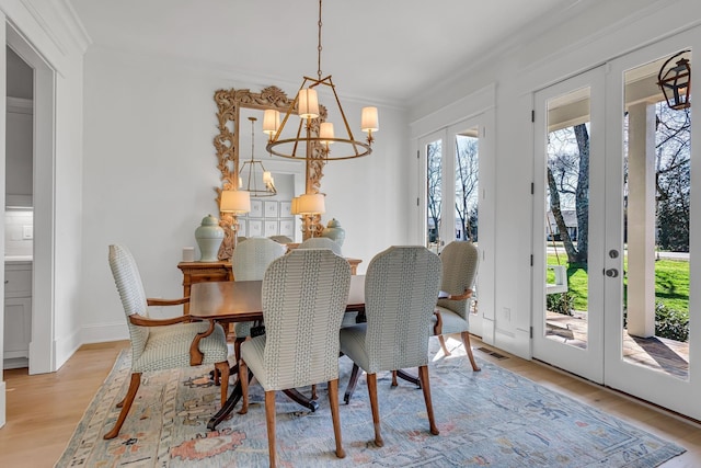 dining space featuring crown molding, visible vents, light wood-style floors, french doors, and an inviting chandelier