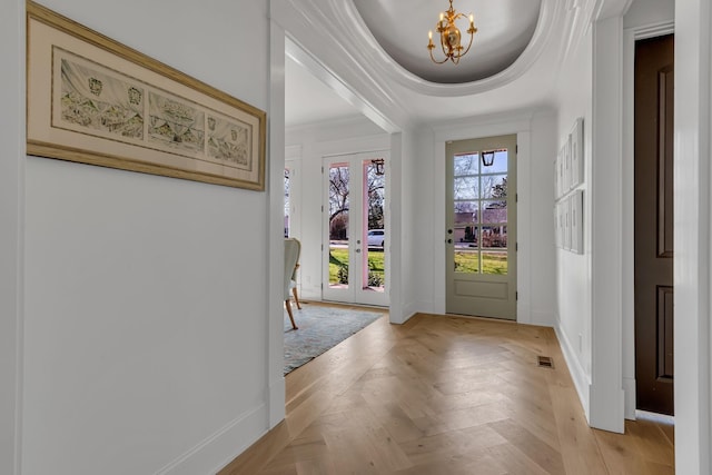 foyer featuring crown molding, visible vents, a notable chandelier, and baseboards