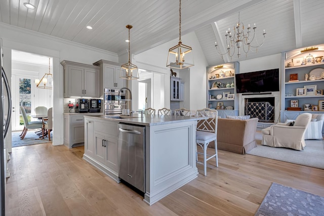 kitchen featuring light wood-style flooring, a kitchen breakfast bar, dishwasher, a center island with sink, and an inviting chandelier