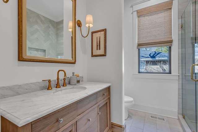 bathroom with toilet, tiled shower, vanity, and visible vents