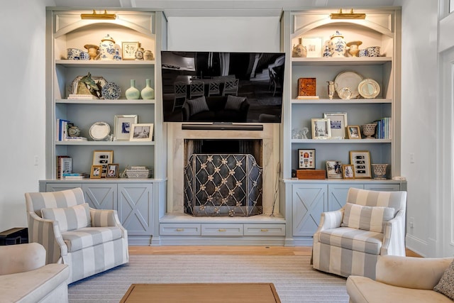 living room featuring built in shelves, a fireplace, and wood finished floors