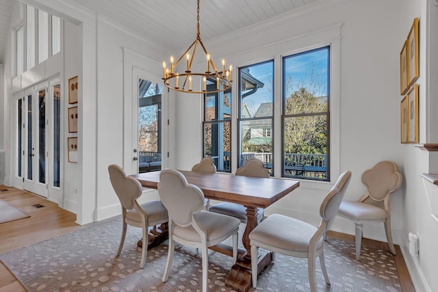 dining space featuring crown molding, baseboards, wood finished floors, and an inviting chandelier