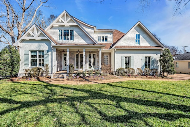 view of front of house featuring stone siding, french doors, a porch, and a front yard