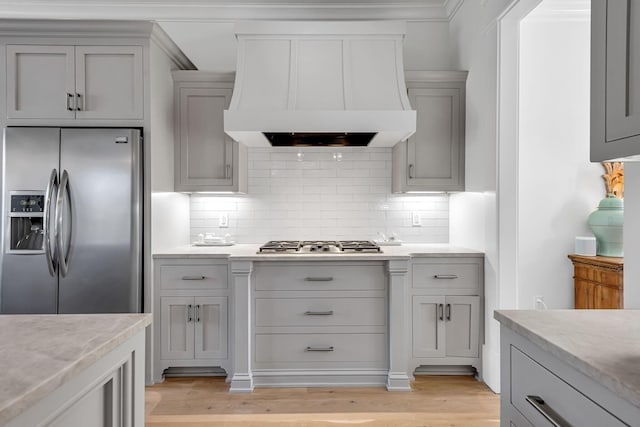 kitchen with stainless steel appliances, tasteful backsplash, custom range hood, gray cabinetry, and light wood-type flooring