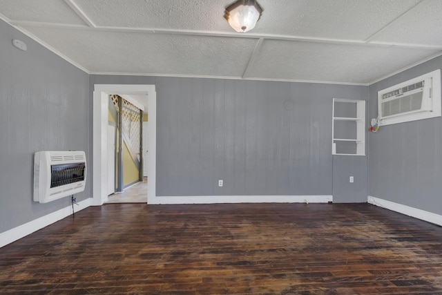 spare room with heating unit, ornamental molding, wood finished floors, and a wall mounted AC