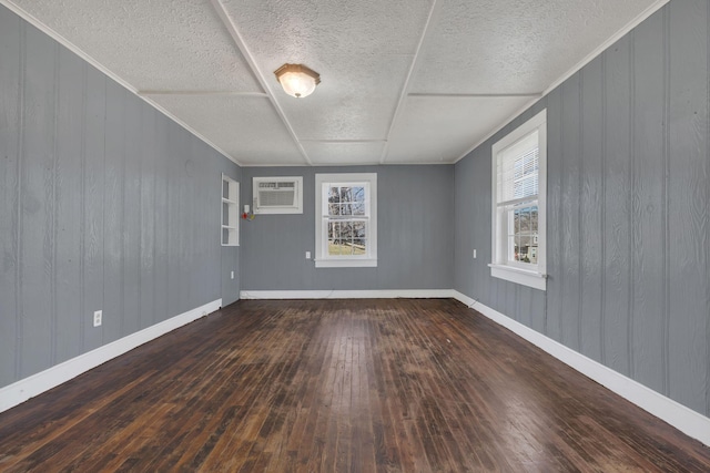 empty room with hardwood / wood-style flooring, a textured ceiling, baseboards, and a wall mounted AC