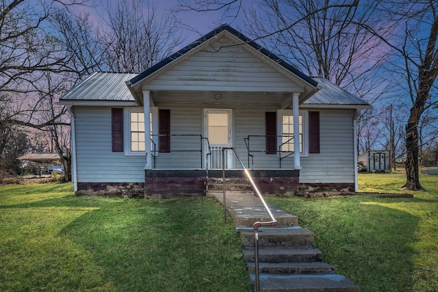 bungalow featuring covered porch, metal roof, and a front lawn