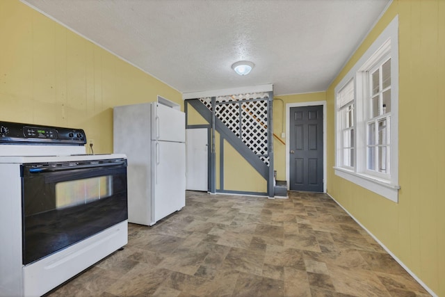 kitchen with a textured ceiling, electric range, wood walls, freestanding refrigerator, and stone finish flooring