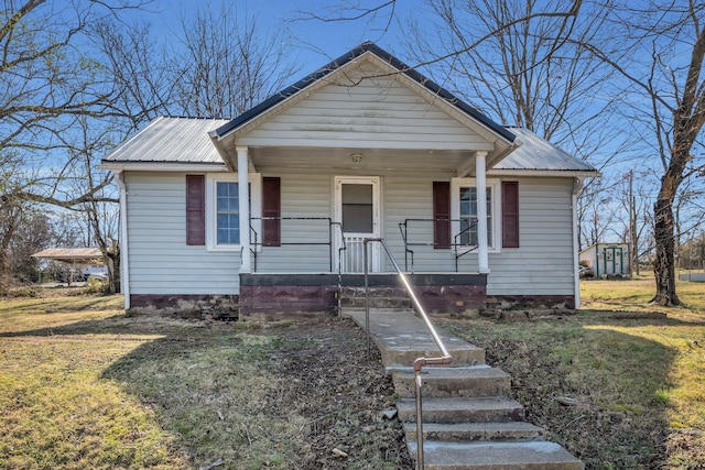 bungalow-style home featuring a front yard, covered porch, and metal roof