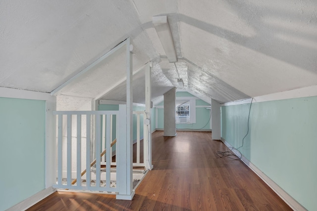 additional living space with a textured ceiling, vaulted ceiling, and wood finished floors