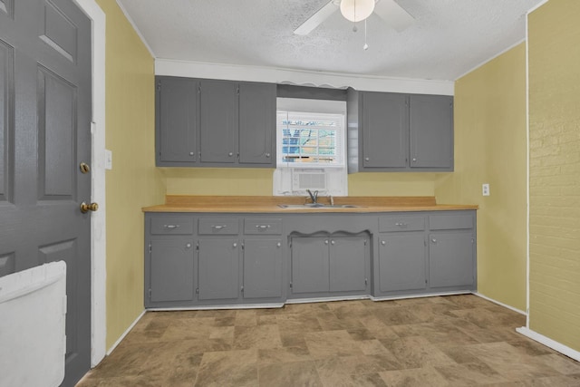 kitchen with a sink, a textured ceiling, and gray cabinetry