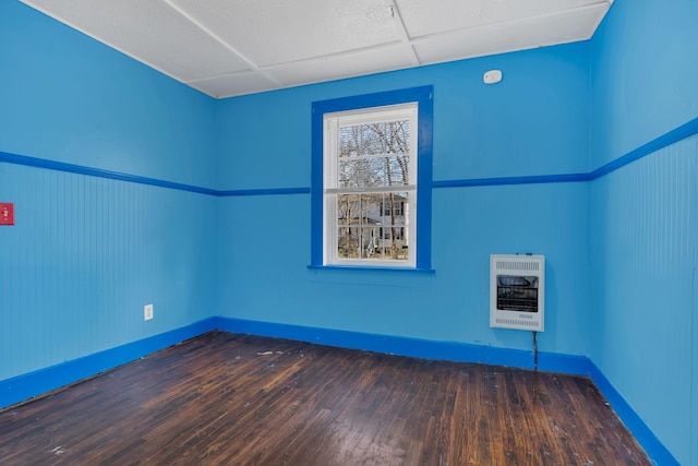 spare room with heating unit, hardwood / wood-style flooring, and a drop ceiling