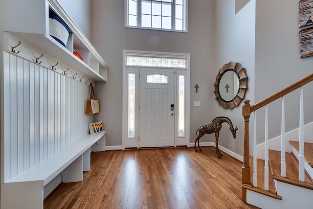 interior space with baseboards, stairs, a high ceiling, and wood finished floors