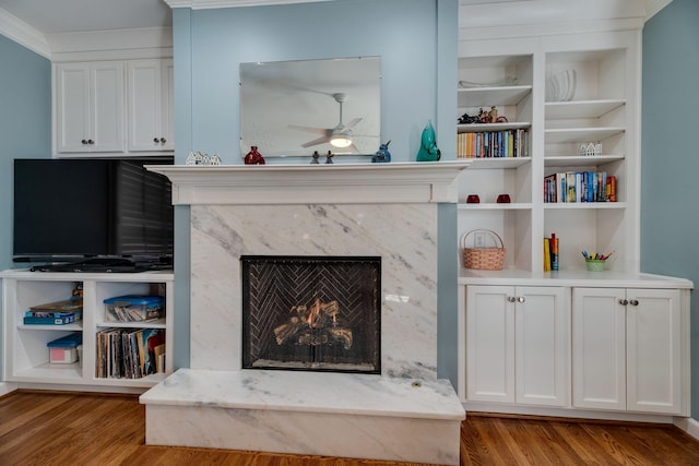 interior details featuring a ceiling fan, a high end fireplace, built in shelves, and wood finished floors