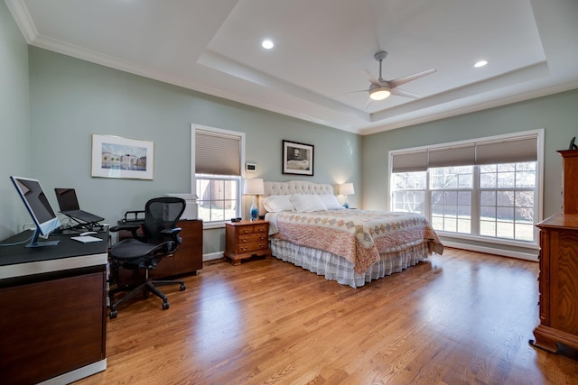 bedroom with ceiling fan, a tray ceiling, crown molding, light wood-style floors, and recessed lighting