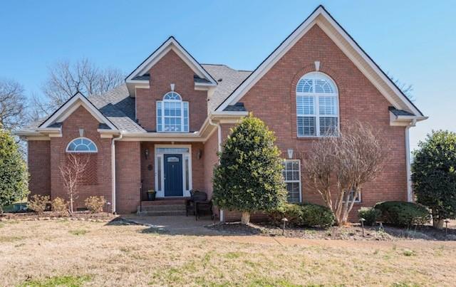 traditional-style home featuring a front yard and brick siding