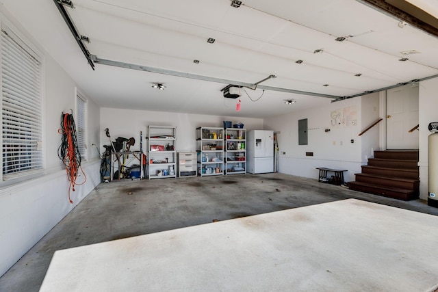 garage with electric panel, white fridge with ice dispenser, and a garage door opener