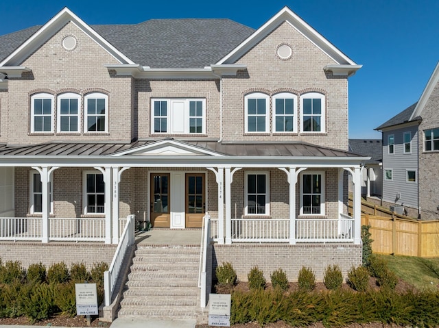 view of front of house featuring a porch, a standing seam roof, and brick siding