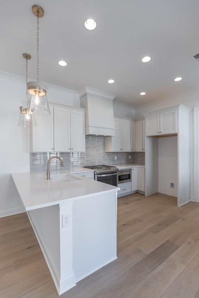 kitchen featuring stainless steel gas stove, light wood-style flooring, a peninsula, built in microwave, and premium range hood