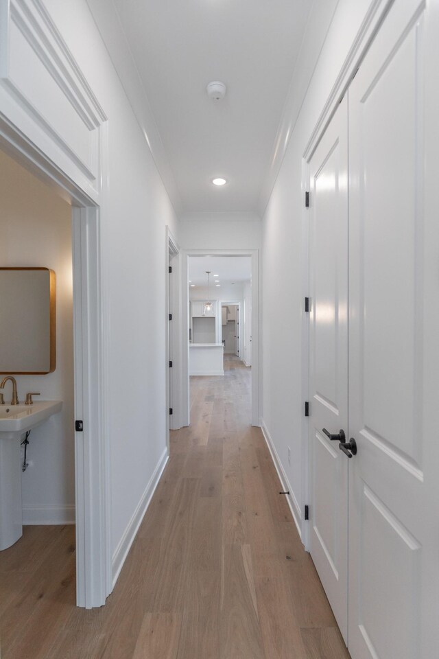 corridor featuring light wood-style flooring and baseboards