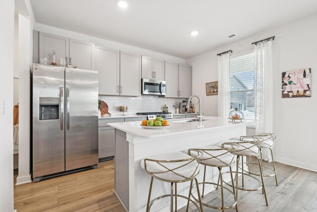 kitchen featuring light countertops, appliances with stainless steel finishes, a sink, and gray cabinetry