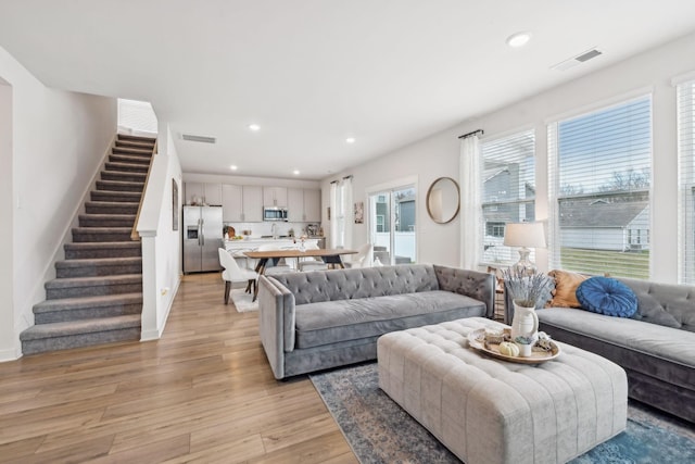 living room featuring light wood-style floors, stairs, visible vents, and recessed lighting