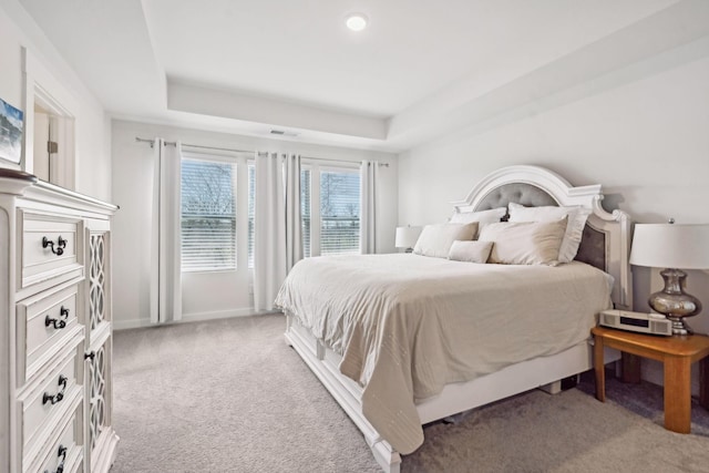 carpeted bedroom with a tray ceiling, visible vents, and baseboards